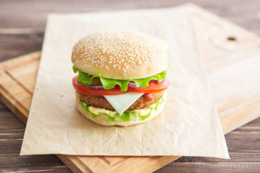 Lezzetli fast food. Ev yapımı hamburger, marul, peynir, biftek ve patates kızartması eski ahşap masaya.