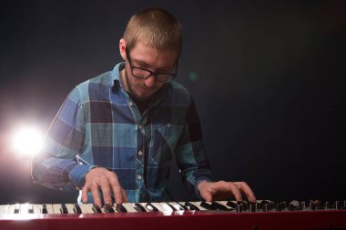 Koyu arkaplanda bir sentezleyiciyle oynayan adam