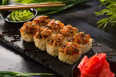 Siyah arka planda wasabi ve zencefilli fırında suşi ruloları. Japon Doğu mutfağı.