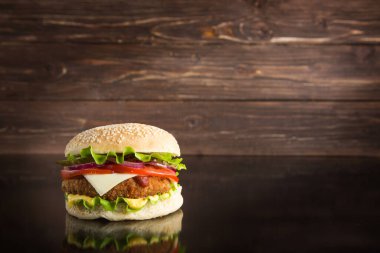 Lezzetli fast food. Tahta arka planda sulu bir çizburger.