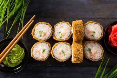 Siyah arka planda wasabi ve zencefilli fırında suşi ruloları. Japon Doğu mutfağı.