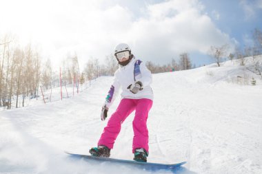 Alplerde snowboard yapan genç bir kadın, açık hava çekimi. Buz gibi kış gününde, yamaçlarda kadın snowboardcu. Kar kenarındaki güzel kız.