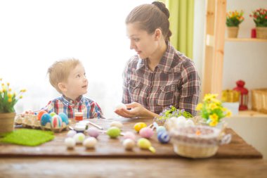 Paskalya konsepti. Mutlu anne ve tatlı çocuğu yumurtaları boyayarak Paskalya için hazırlanıyorlar..