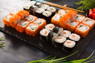 Siyah arka planda wasabi ve zencefilli suşi ruloları. Japon Doğu mutfağı.