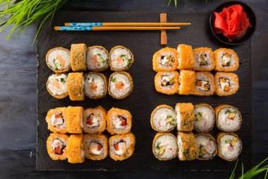 Siyah arka planda wasabi ve zencefilli fırında suşi ruloları. Japon Doğu mutfağı.