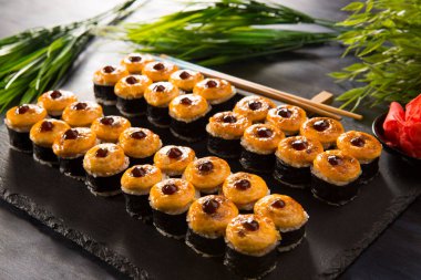 Siyah arka planda wasabi ve zencefilli fırında suşi ruloları. Japon Doğu mutfağı.