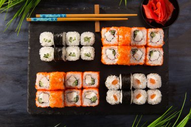 Siyah arka planda wasabi ve zencefilli suşi ruloları. Japon Doğu mutfağı.