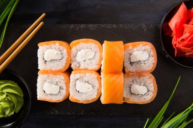 Siyah arka planda wasabi ve zencefilli suşi ruloları. Japon Doğu mutfağı.