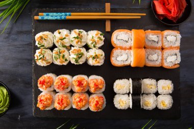 Siyah arka planda wasabi ve zencefilli suşi ruloları. Japon Doğu mutfağı.