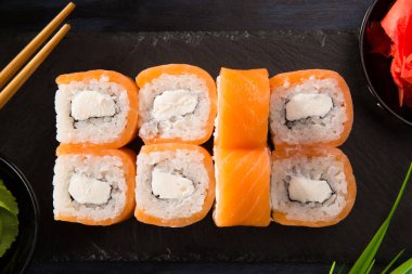 Siyah arka planda wasabi ve zencefilli suşi ruloları. Japon Doğu mutfağı.