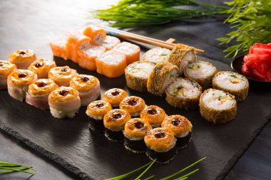 Siyah arka planda wasabi ve zencefilli fırında suşi ruloları. Japon Doğu mutfağı.