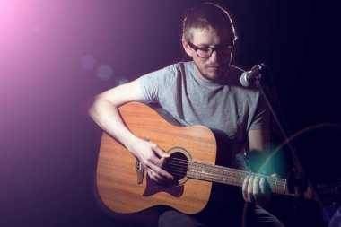 Gitar çalan ve arka planda şarkı söyleyen şarkıcı.