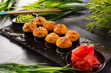 Siyah arka planda wasabi ve zencefilli fırında suşi ruloları. Japon Doğu mutfağı.