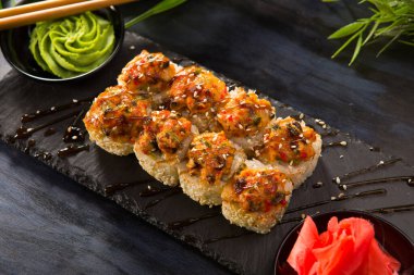 Siyah arka planda wasabi ve zencefilli fırında suşi ruloları. Japon Doğu mutfağı.