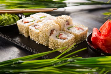 Siyah arka planda wasabi ve zencefilli suşi ruloları. Japon Doğu mutfağı.