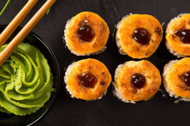 Siyah arka planda wasabi ve zencefilli fırında suşi ruloları. Japon Doğu mutfağı.