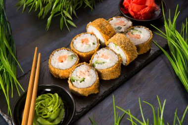 Siyah arka planda wasabi ve zencefilli fırında suşi ruloları. Japon Doğu mutfağı.