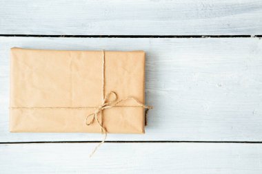 Noel tarzı, iplerle bağlanmış, taşralı, kahverengi kağıt paketi kapat. Beyaz ahşap zemin.