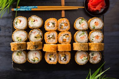 Siyah arka planda wasabi ve zencefilli fırında suşi ruloları. Japon Doğu mutfağı.