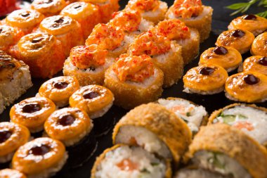 Siyah arka planda wasabi ve zencefilli fırında suşi ruloları. Japon Doğu mutfağı.