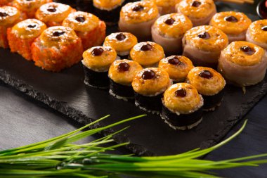 Siyah arka planda wasabi ve zencefilli fırında suşi ruloları. Japon Doğu mutfağı.