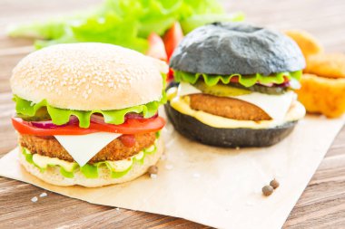 Lezzetli fast food. İki hamburger, sığır burger pirzolası, kızarmış soğan, ıspanak, ketçap sosu ve mavi peynirli geleneksel çörekler, koyu ahşap zemin üzerinde ahşap kesme tahtasında servis ediliyor..