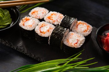 Siyah arka planda wasabi ve zencefilli suşi ruloları. Japon Doğu mutfağı.