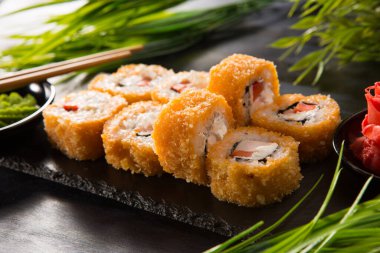 Siyah arka planda wasabi ve zencefilli fırında suşi ruloları. Japon Doğu mutfağı.