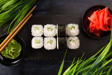 Siyah arka planda wasabi ve zencefilli suşi ruloları. Japon Doğu mutfağı.