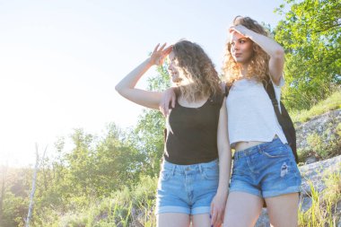 Sınırları olmayan bir dünya. Dağlarda iki kızın çarpıcı yolculuğu. Yaz yürüyüşü sırasında gün batımında dağın tepesinde iki mutlu kız turist.