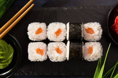 Siyah arka planda wasabi ve zencefilli suşi ruloları. Japon Doğu mutfağı.