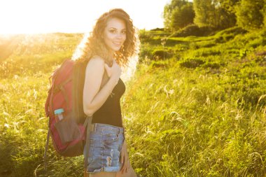 Sınırları olmayan bir dünya. Dağlardaki kızın çarpıcı yolculuğu. Sırt çantalı şık hippi kadın yazın muhteşem ormanlara ve dağlara bakıyor. Seyahat konsepti.