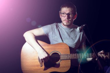 Gitar çalan ve arka planda şarkı söyleyen şarkıcı.