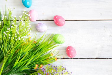 Paskalya yumurtaları ve çiçekler beyaz ahşap kalaslarda