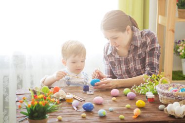 Anne ve oğlu Paskalya yumurtası boyuyor. Mutlu aile Paskalya için hazırlanıyor..