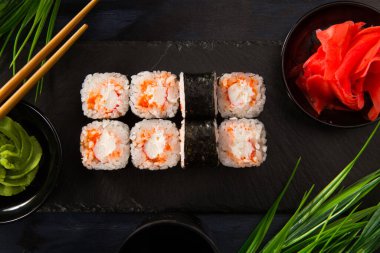Siyah arka planda wasabi ve zencefilli suşi ruloları. Japon Doğu mutfağı.