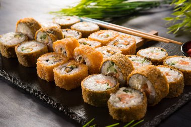 Siyah arka planda wasabi ve zencefilli fırında suşi ruloları. Japon Doğu mutfağı.