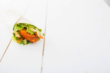 Tahta masanın üzerinde tavuk ve sebzeli lezzetli bir dürüm sandviç.