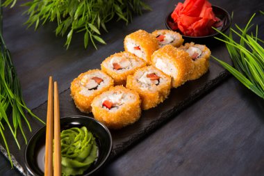 Siyah arka planda wasabi ve zencefilli fırında suşi ruloları. Japon Doğu mutfağı.