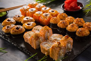 Siyah arka planda wasabi ve zencefilli fırında suşi ruloları. Japon Doğu mutfağı.