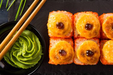 Siyah arka planda wasabi ve zencefilli fırında suşi ruloları. Japon Doğu mutfağı.