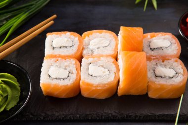 Siyah arka planda wasabi ve zencefilli suşi ruloları. Japon Doğu mutfağı.