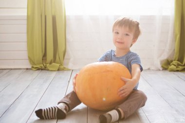 Harika küçük çocuk büyük balkabağıyla oturuyor. Çocuklar Cadılar Bayramı 'nı oturma odasında kutluyorlar. Mutlu Cadılar Bayramı Mutlu Cadılar Bayramı