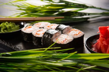 Siyah arka planda wasabi ve zencefilli suşi ruloları. Japon Doğu mutfağı.