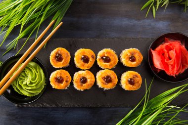 Siyah arka planda wasabi ve zencefilli fırında suşi ruloları. Japon Doğu mutfağı.