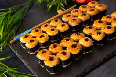 Siyah arka planda wasabi ve zencefilli fırında suşi ruloları. Japon Doğu mutfağı.