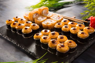 Siyah arka planda wasabi ve zencefilli fırında suşi ruloları. Japon Doğu mutfağı.