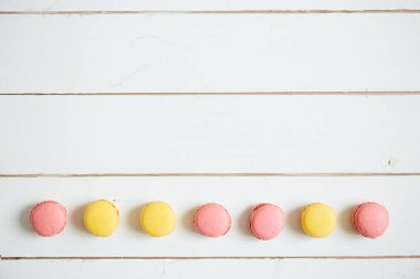 Beyaz ahşap masada tatlı renkli Fransız kurabiyeleri.