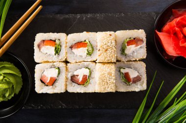 Siyah arka planda wasabi ve zencefilli suşi ruloları. Japon Doğu mutfağı.