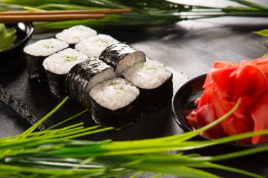 Siyah arka planda wasabi ve zencefilli suşi ruloları. Japon Doğu mutfağı.